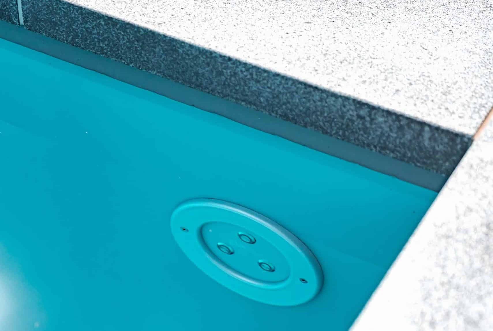 Lang, modern zwembad met lichte boordstenen in een strak aangelegde tuin bij een designvilla.